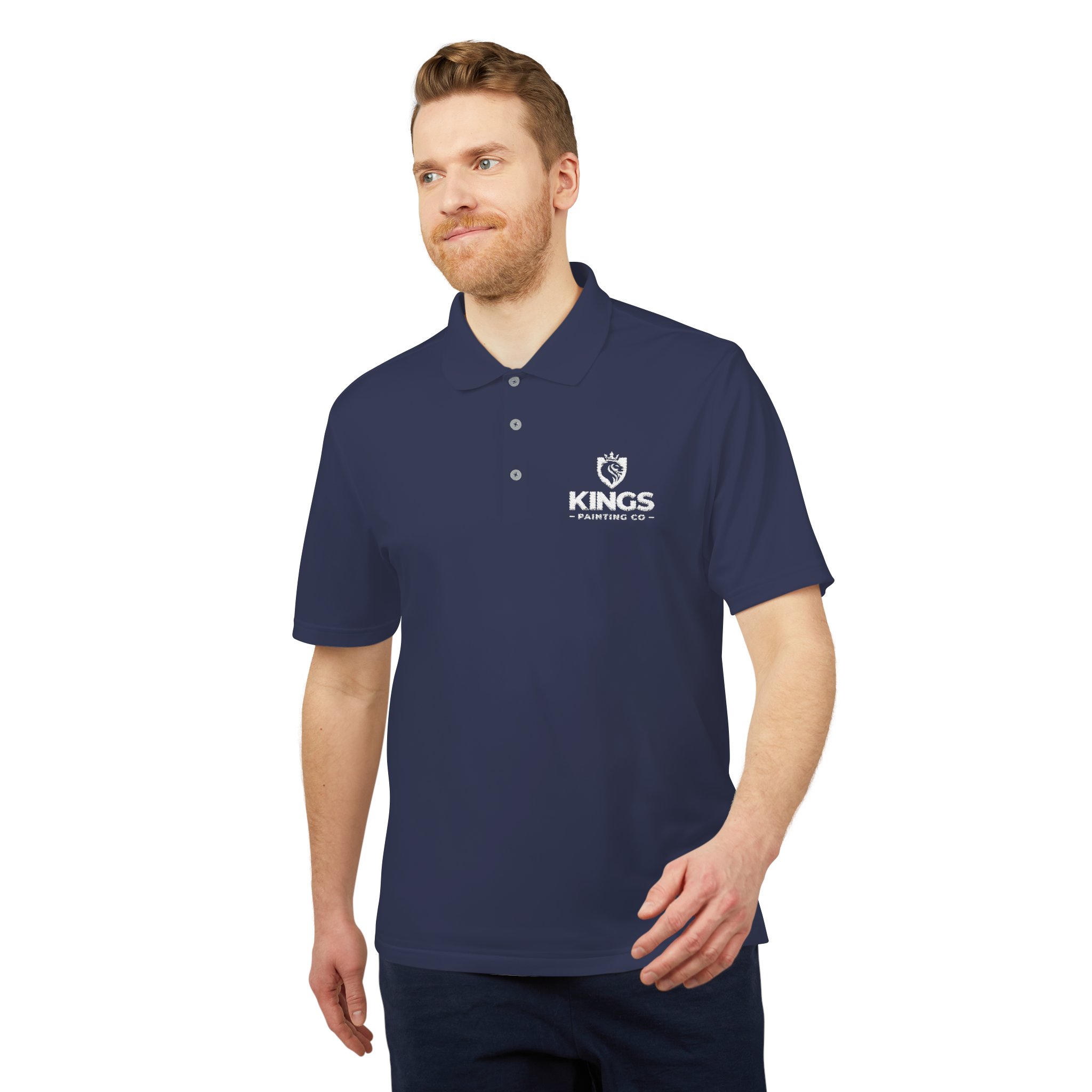 A man with light hair and a beard wears the Kings Painting Co. Performance Polo by Under Armour®, featuring a white logo on the left chest, standing against a white background.