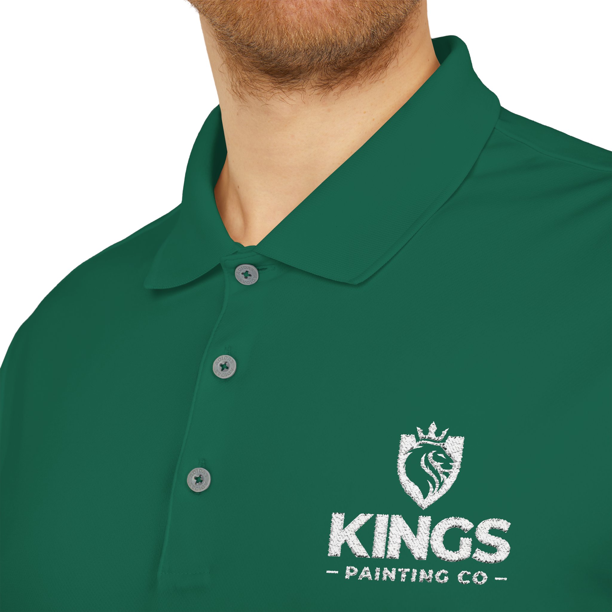 A person wearing the Kings Painting Co. Performance Polo by Under Armour®, featuring a green color and a white embroidered KINGS PAINTING CO name with a lion crest logo on the chest.