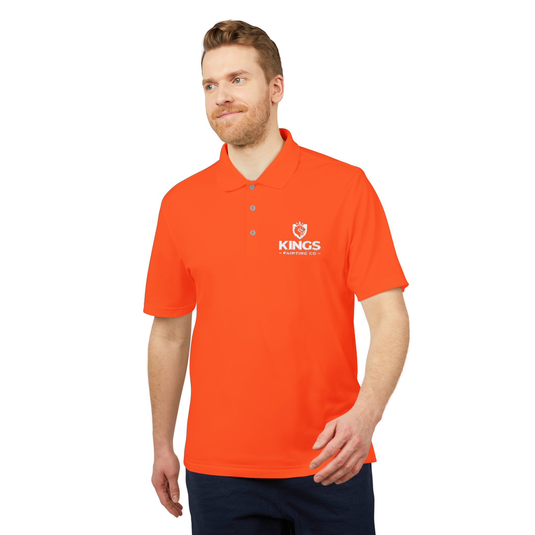 A man wearing an orange Kings Painting Co. Performance Polo by Under Armour® with a white logo on the left chest stands against a white background.