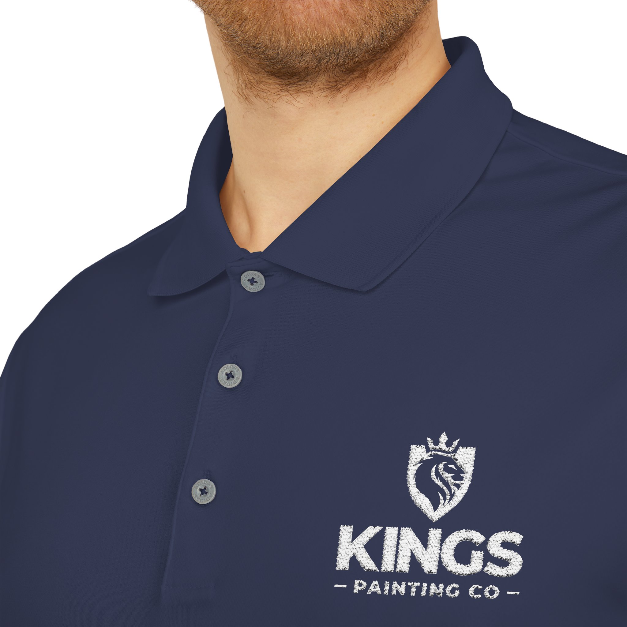 A man is shown wearing the Kings Painting Co. Performance Polo by Under Armour®, featuring a white embroidered KINGS PAINTING CO name and lion logo on the chest; only his lower face and upper torso are visible.