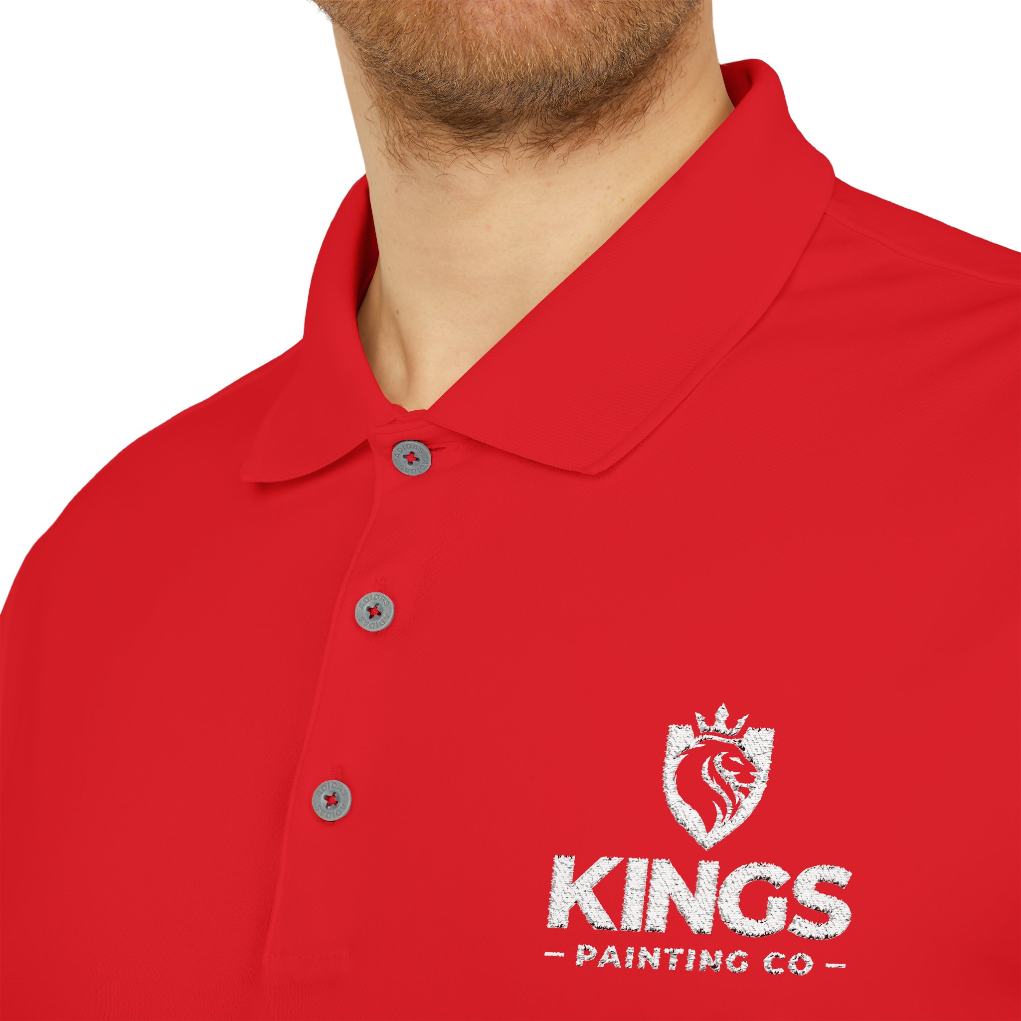 A person wearing the Kings Painting Co. Performance Polo by Under Armour®, featuring a bright red color with a white embroidered lion crest and the words "KINGS PAINTING CO" on the left side.