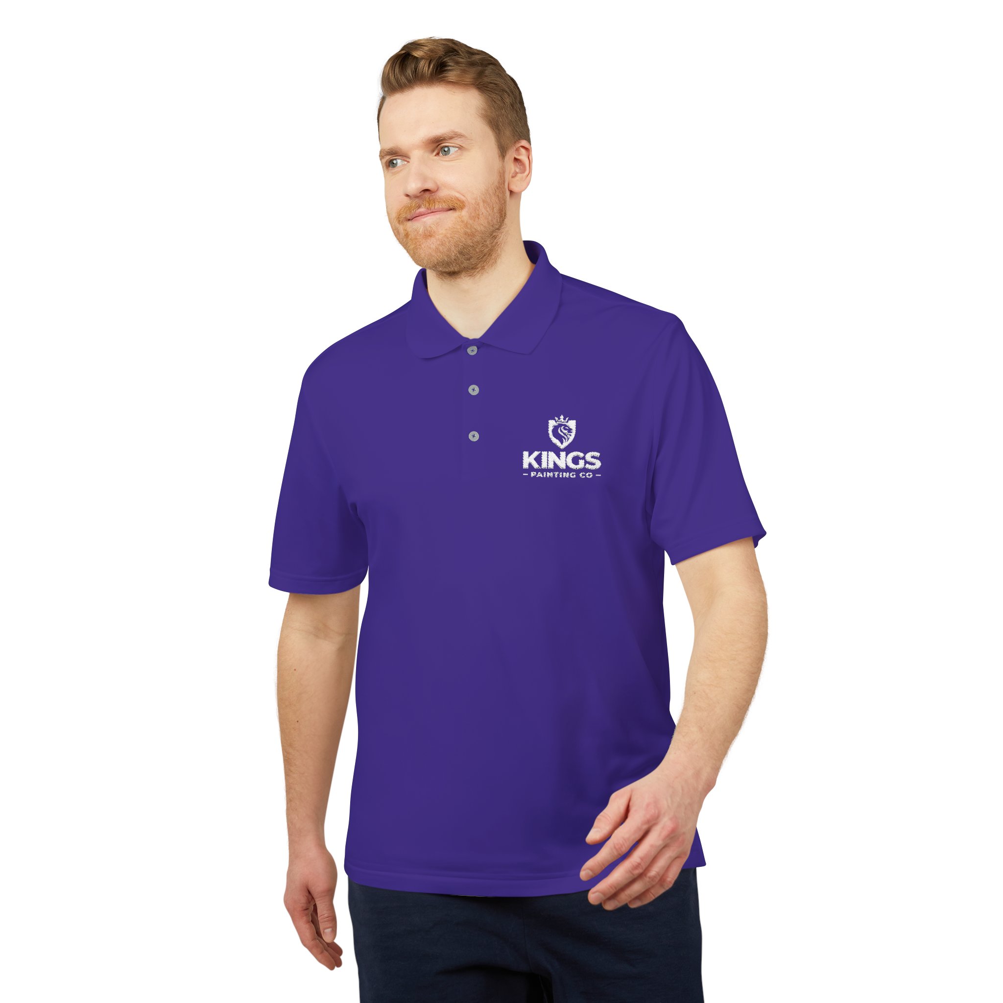 A man wearing a purple Kings Painting Co. Performance Polo by Under Armour®, featuring a white logo on the left chest, stands against a white background, looking slightly to the side.