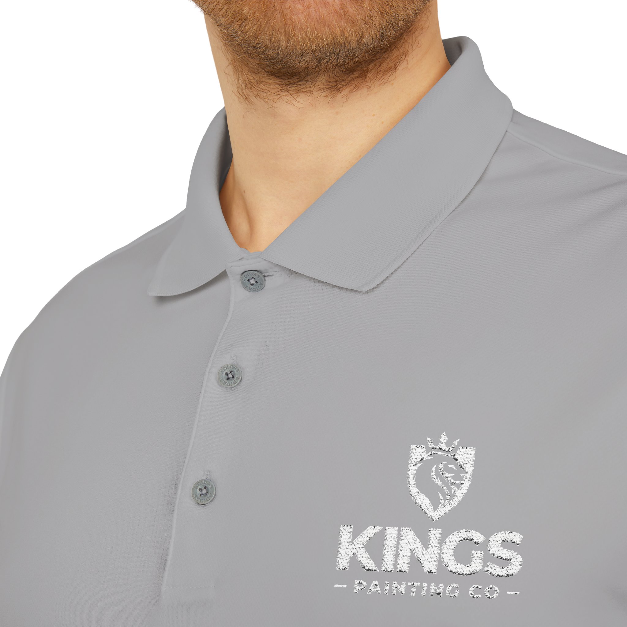 A person wearing a light gray Kings Painting Co. Performance Polo by Under Armour®, featuring a white KINGS PAINTING CO and lion crest logo embroidered on the left chest. The photo is cropped at the nose and below the shoulders.